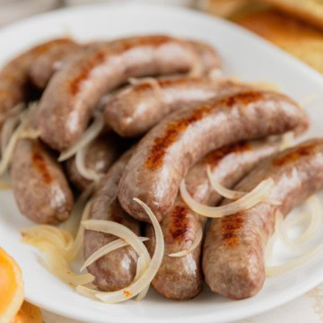 Plate filled with baked brats and onions.