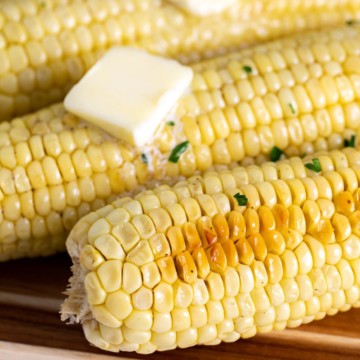 Baked corn on the cob with butter and chopped parsley.