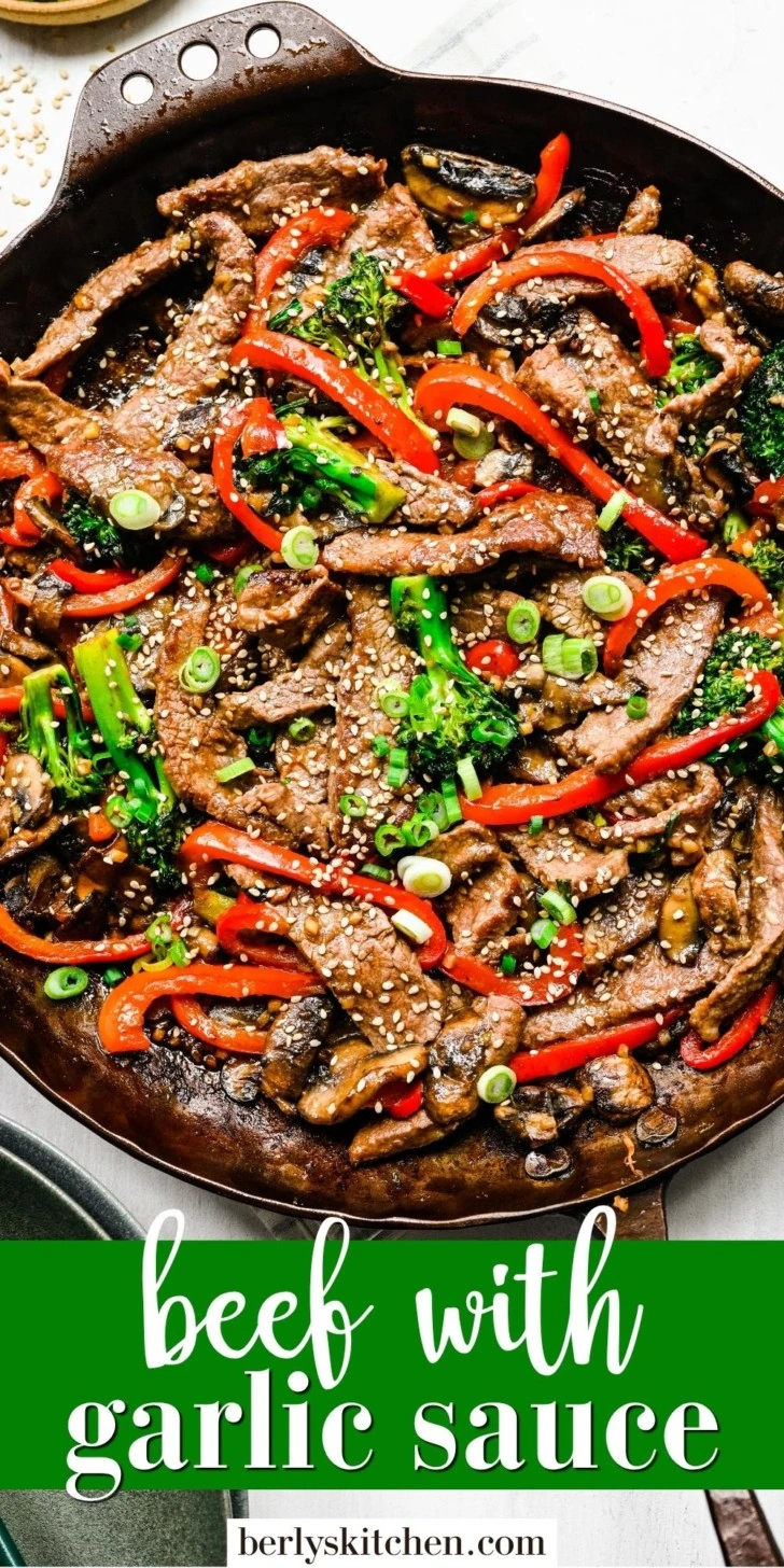 Close up view of beef with garlic sauce topped with sesame seeds.