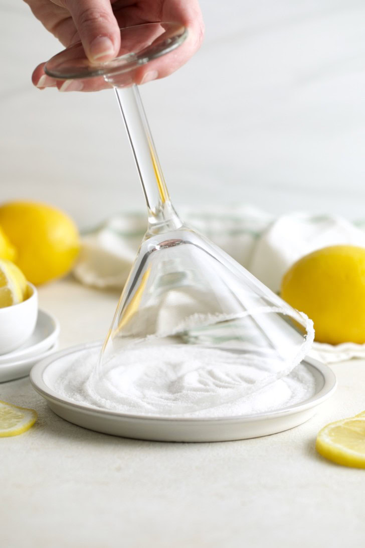 Martini glass rim being dipped in sugar for a lemon cocktail.