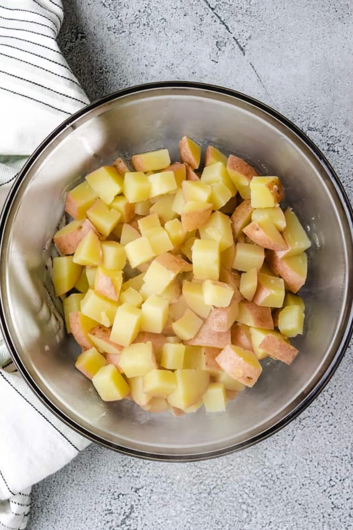 Cooked red potatoes draining in a glass bowl.