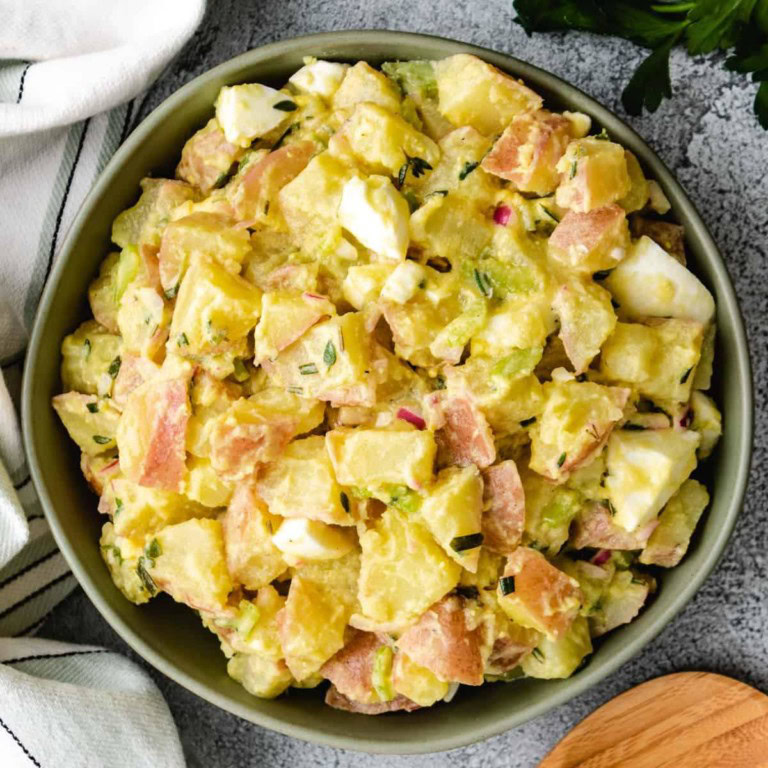 Potato salad with mustard vinaigrette served in a green bowl.