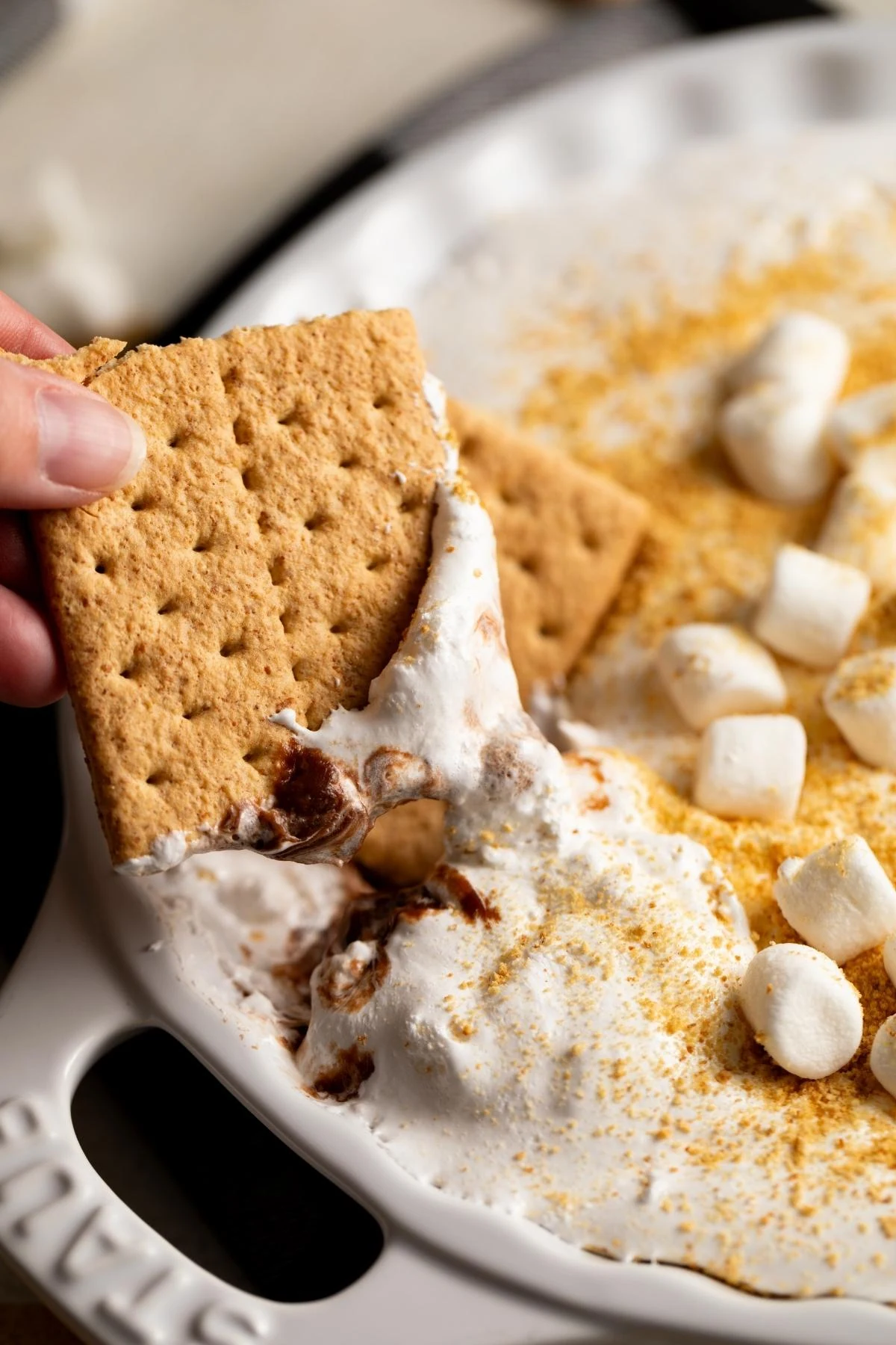 Close-up of a graham cracker dipped into s’mores dip.