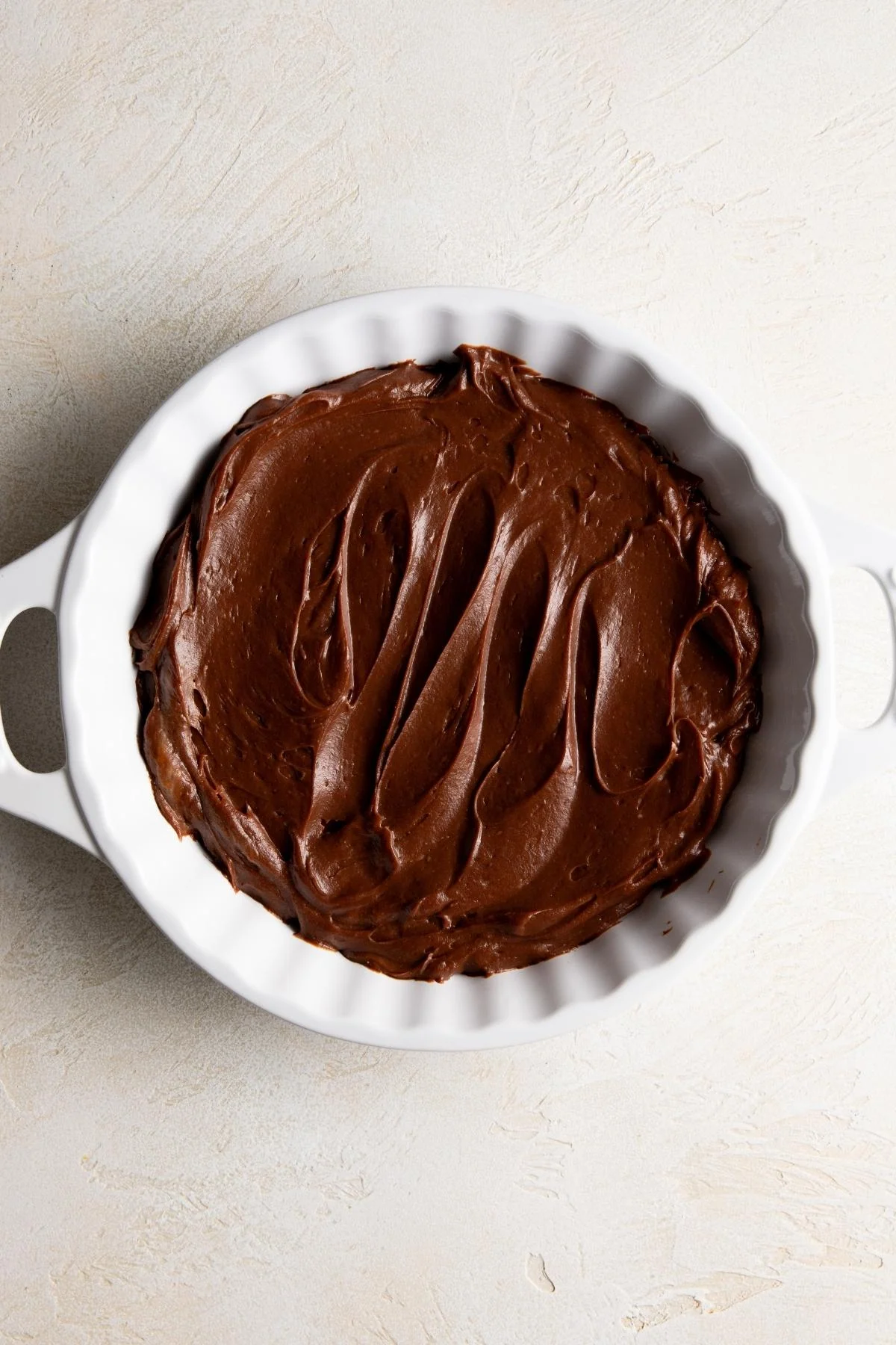 Chocolate layer spread in a white pie dish.