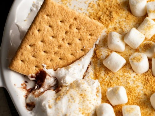 Close-up of a graham cracker dipped into s&rsquo;mores dip.