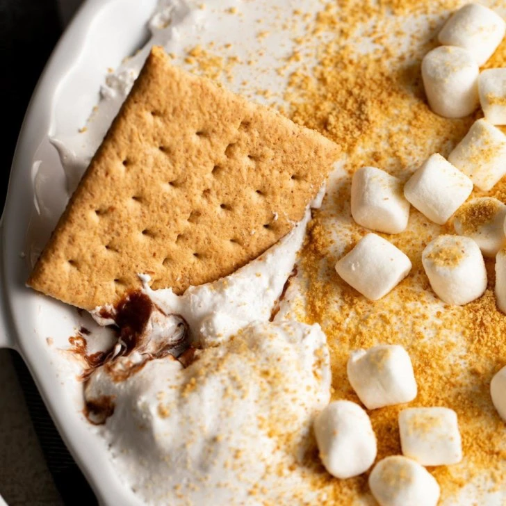 Close-up of a graham cracker dipped into s’mores dip.