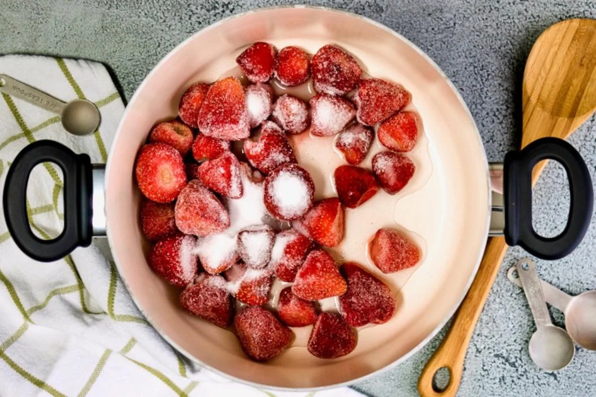 Frozen strawberries with sugar in a saucepan.