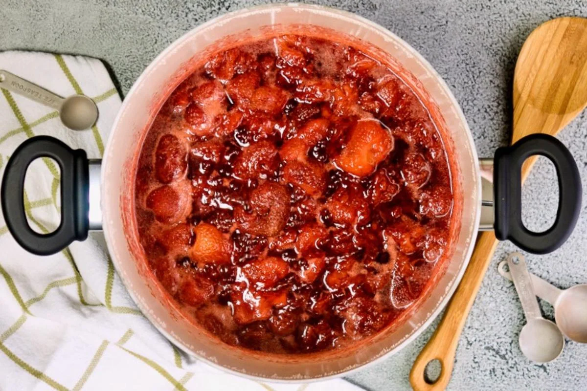 Strawberry jam simmering in a saucepan.