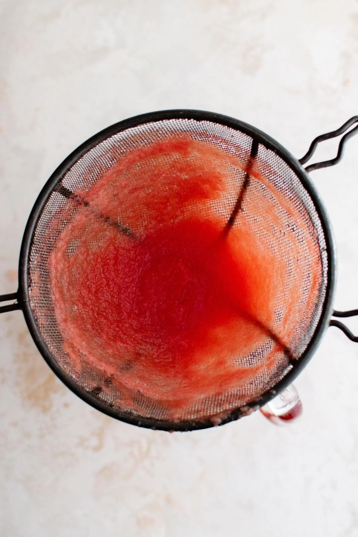 Agua fresca poured through a mesh strainer.