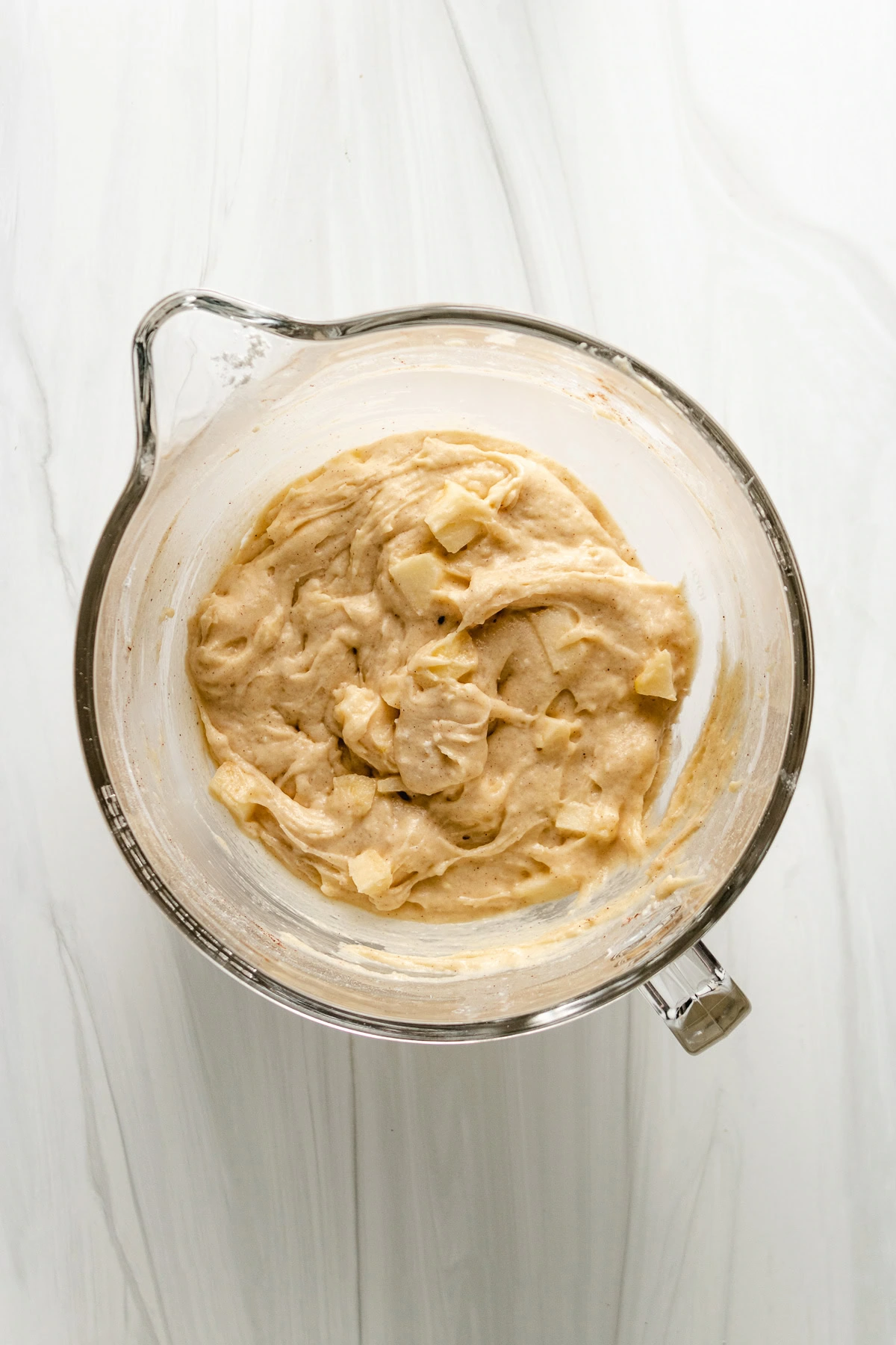 Mixing bowl filled with gluten free muffin batter and diced apples.