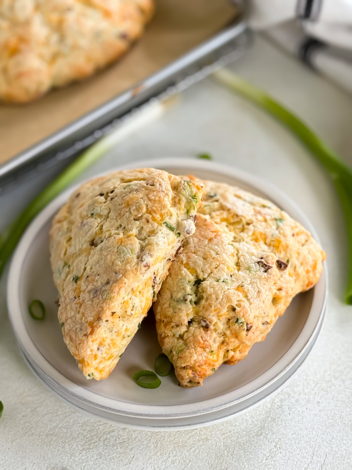 Two bacon cheddar scones on a stack of plates.