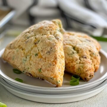 Close up view of bacon cheddar scones on a stack of plates.