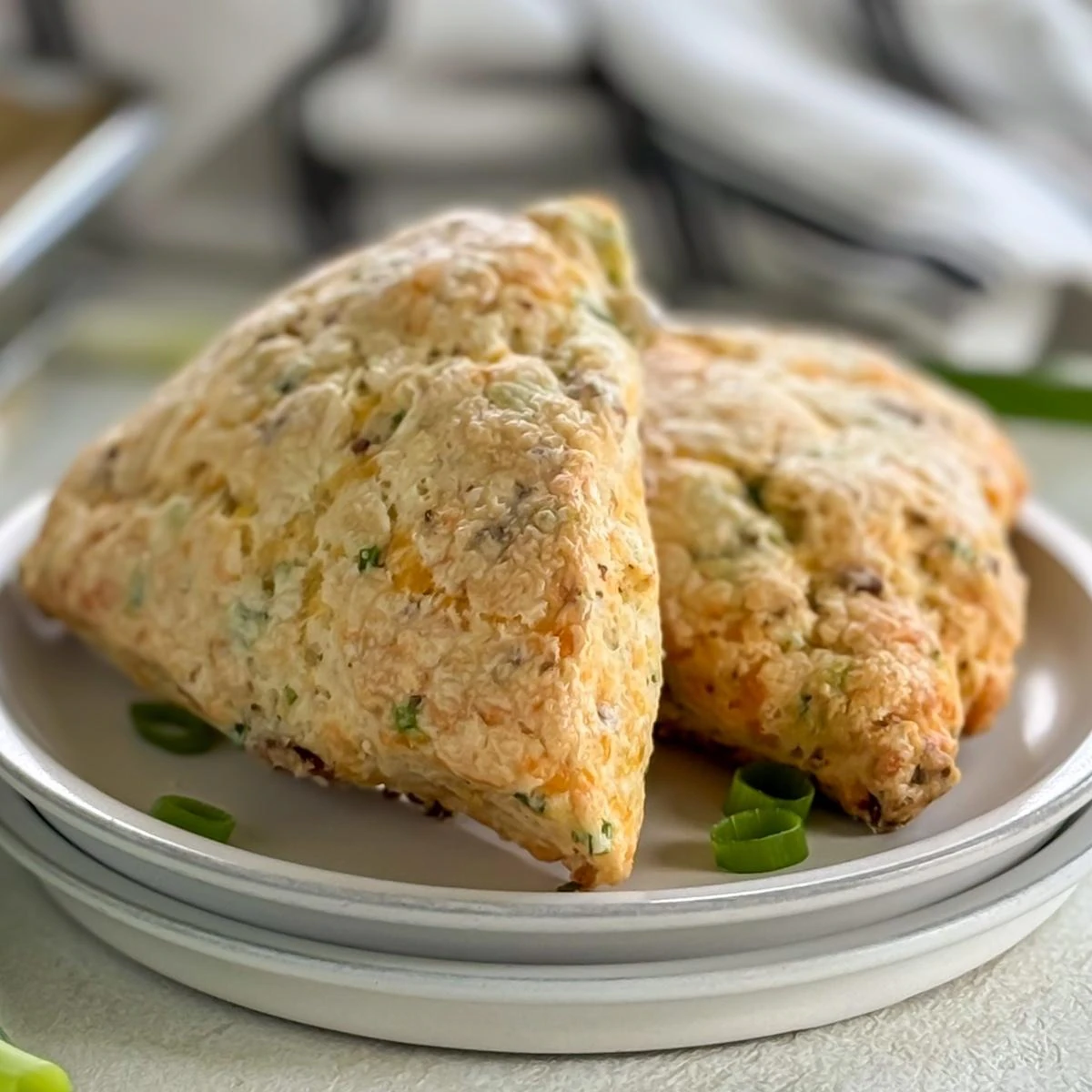 Close up view of bacon cheddar scones on a stack of plates.