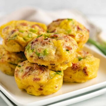 Bacon and egg muffins piled on a white plate.