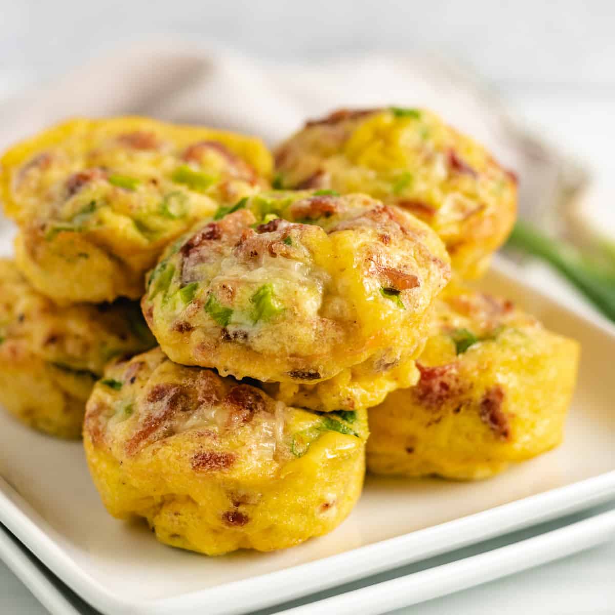 Bacon and egg muffins piled on a white plate.