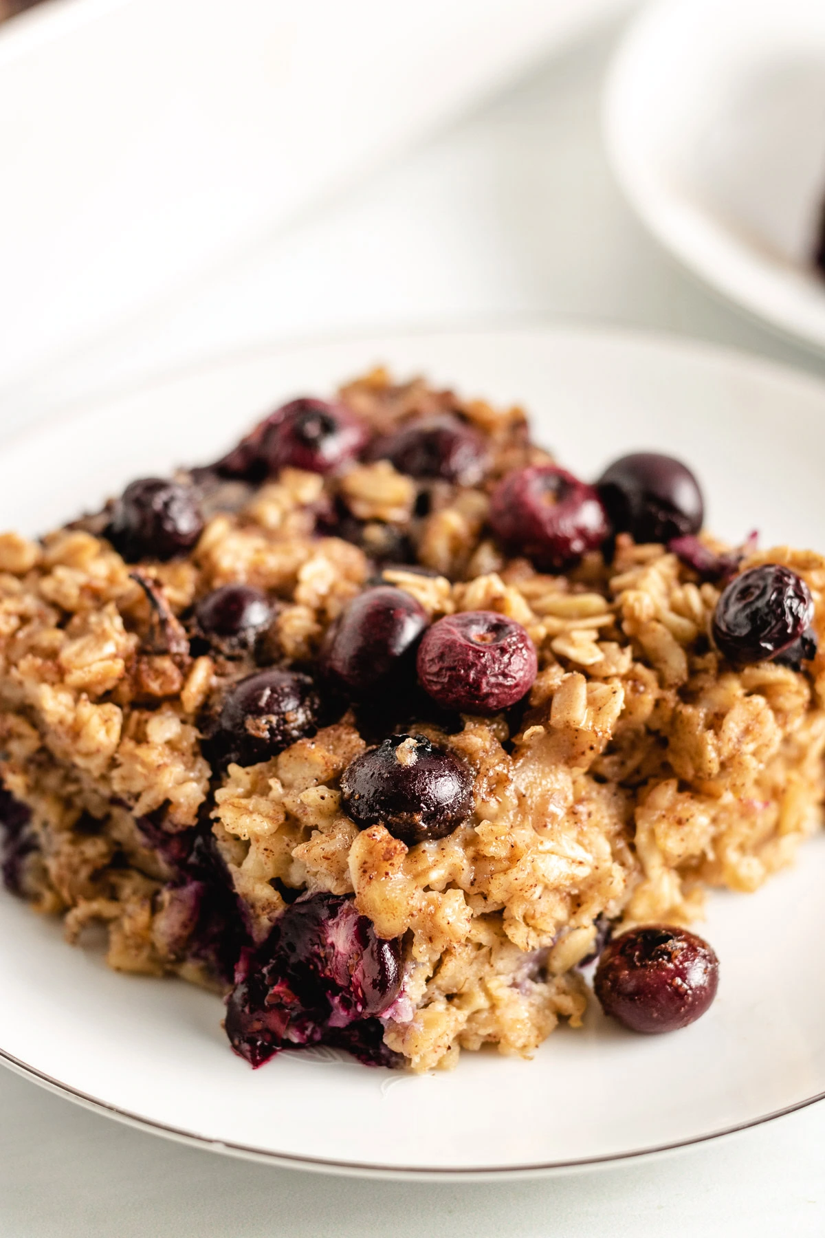 Close up view of blueberry baked oatmeal on a white plate.