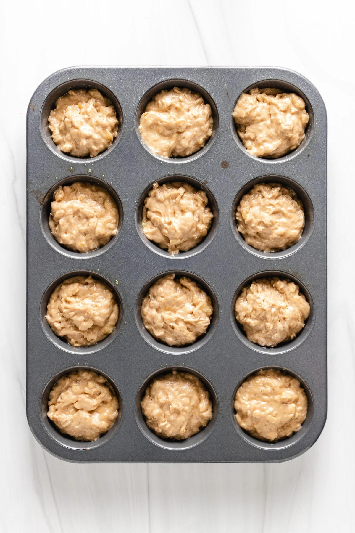 Banana oat muffin batter in a muffin pan.