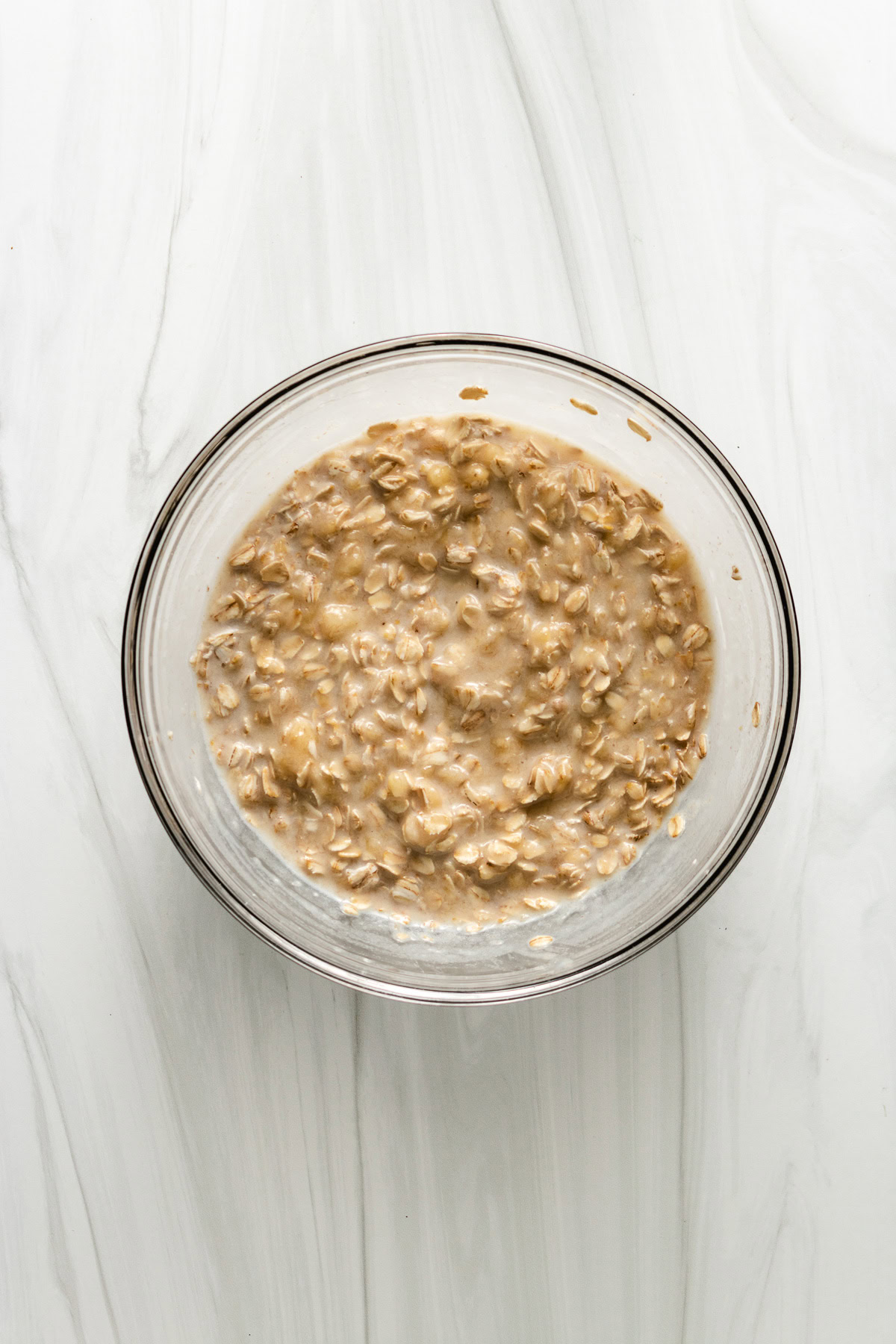 Mashed bananas, milk, and oats mixed together in a bowl.