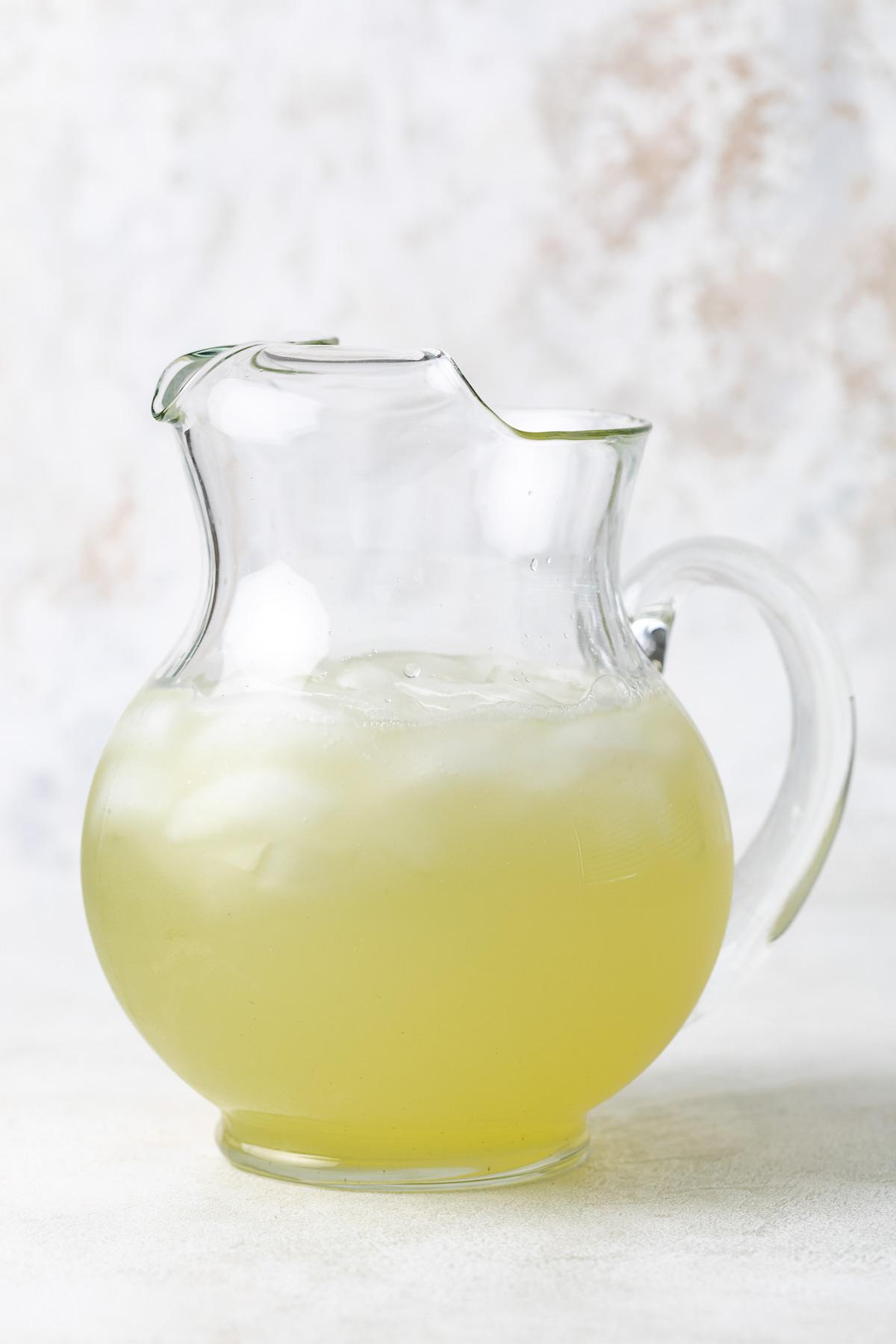 Basil lemonade in a large glass pitcher.