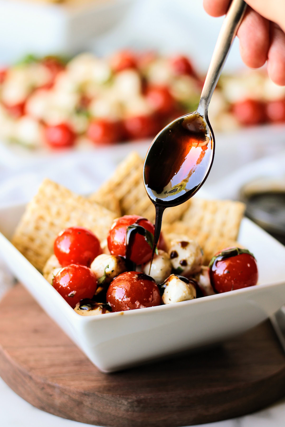 Balsamic glaze being drizzled over fresh caprese salad.