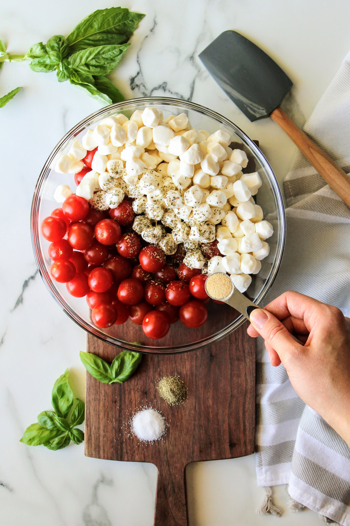 Seasonings being added to caprese salad.