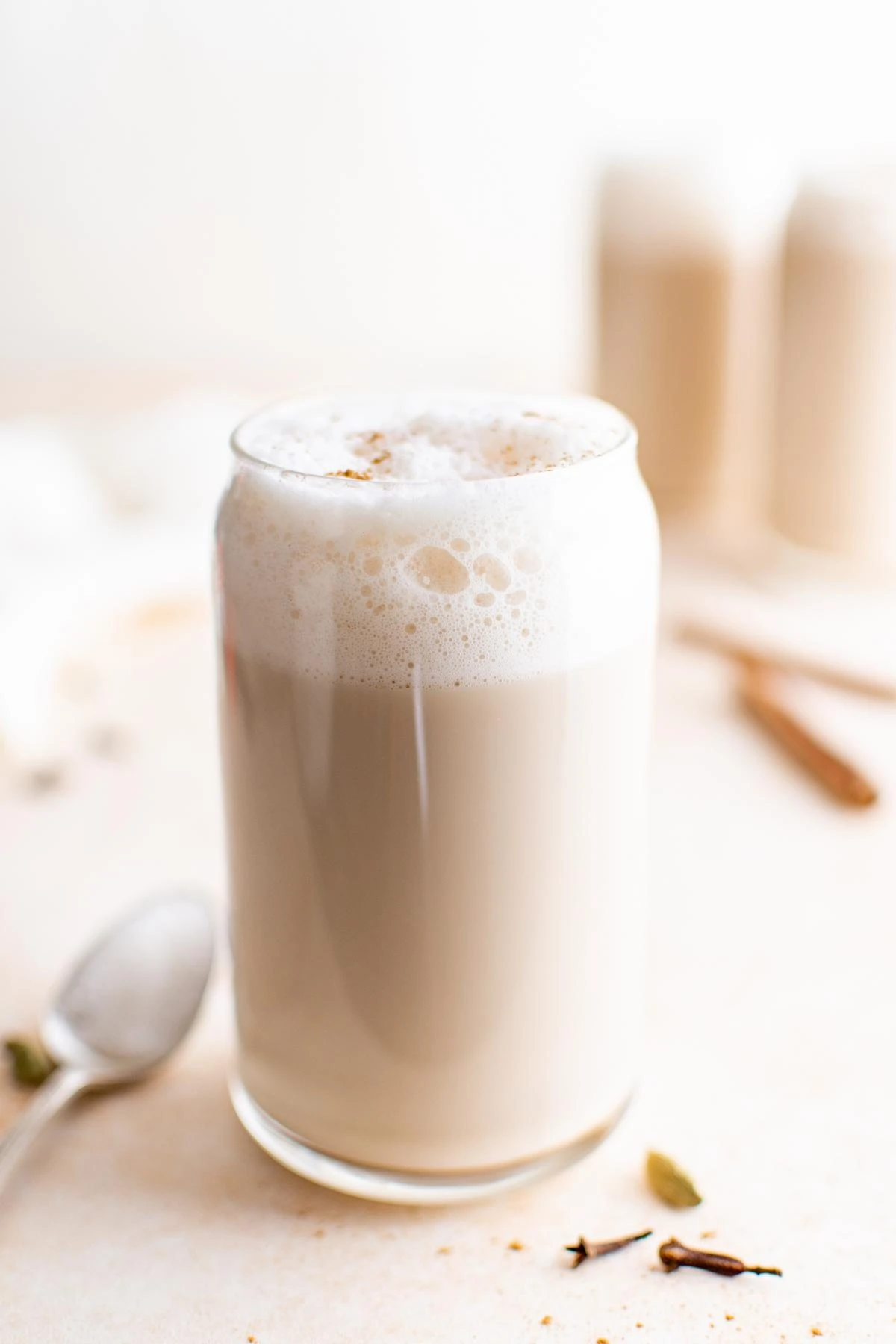Creamy chai latte topped with foam in a clear glass.