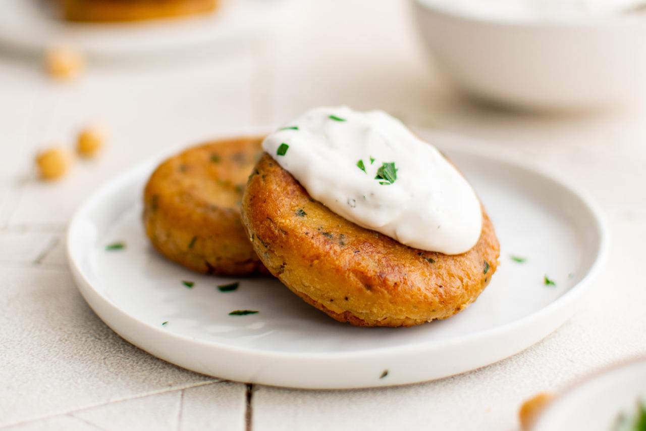 Two chickpea fritters on a plate with a creamy sauce.