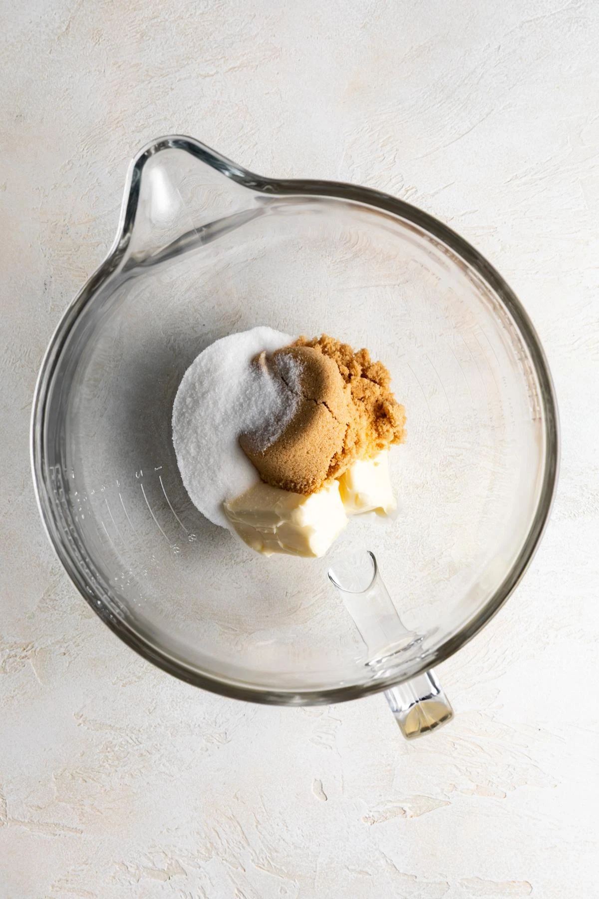 Two kinds of sugar and softened butter in a mixing bowl.
