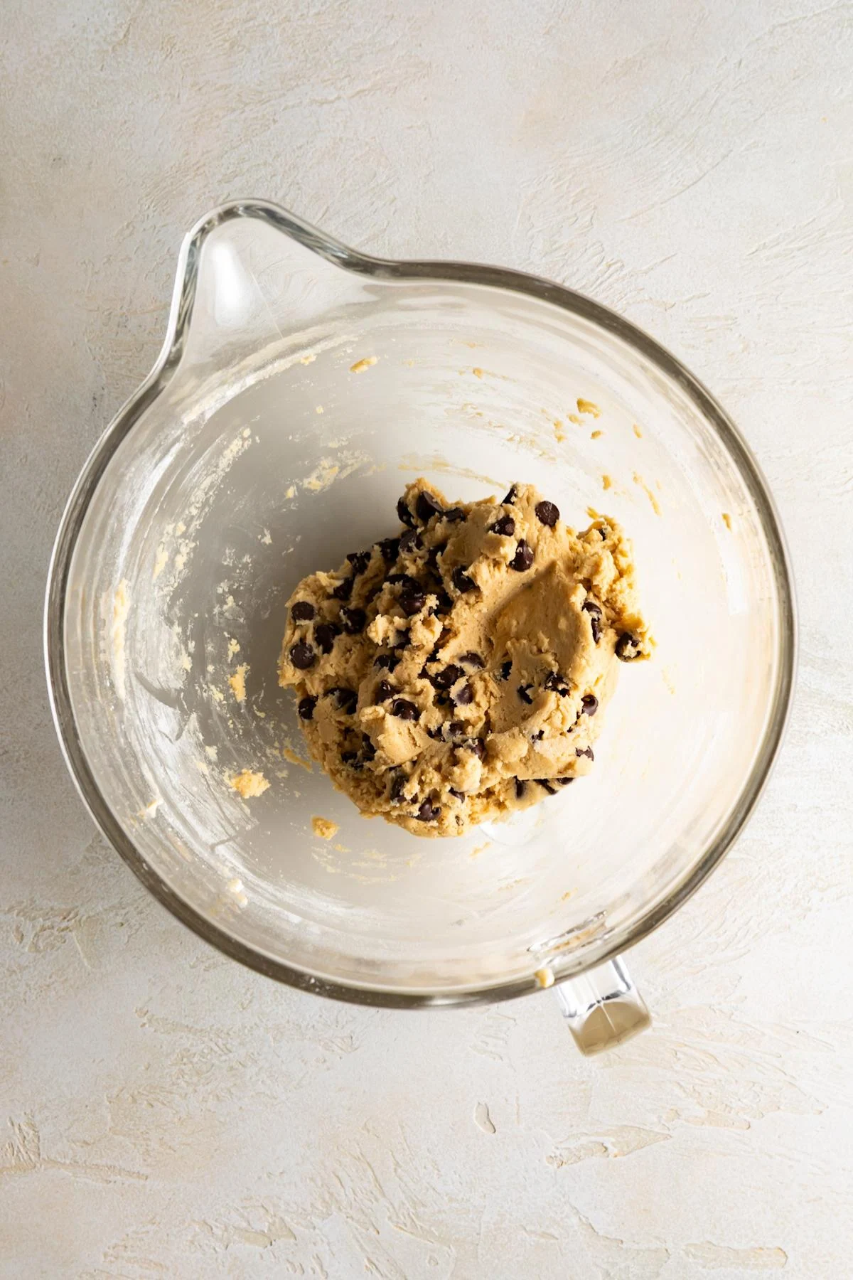 Chocolate chip cookie dough in a glass mixing bowl.