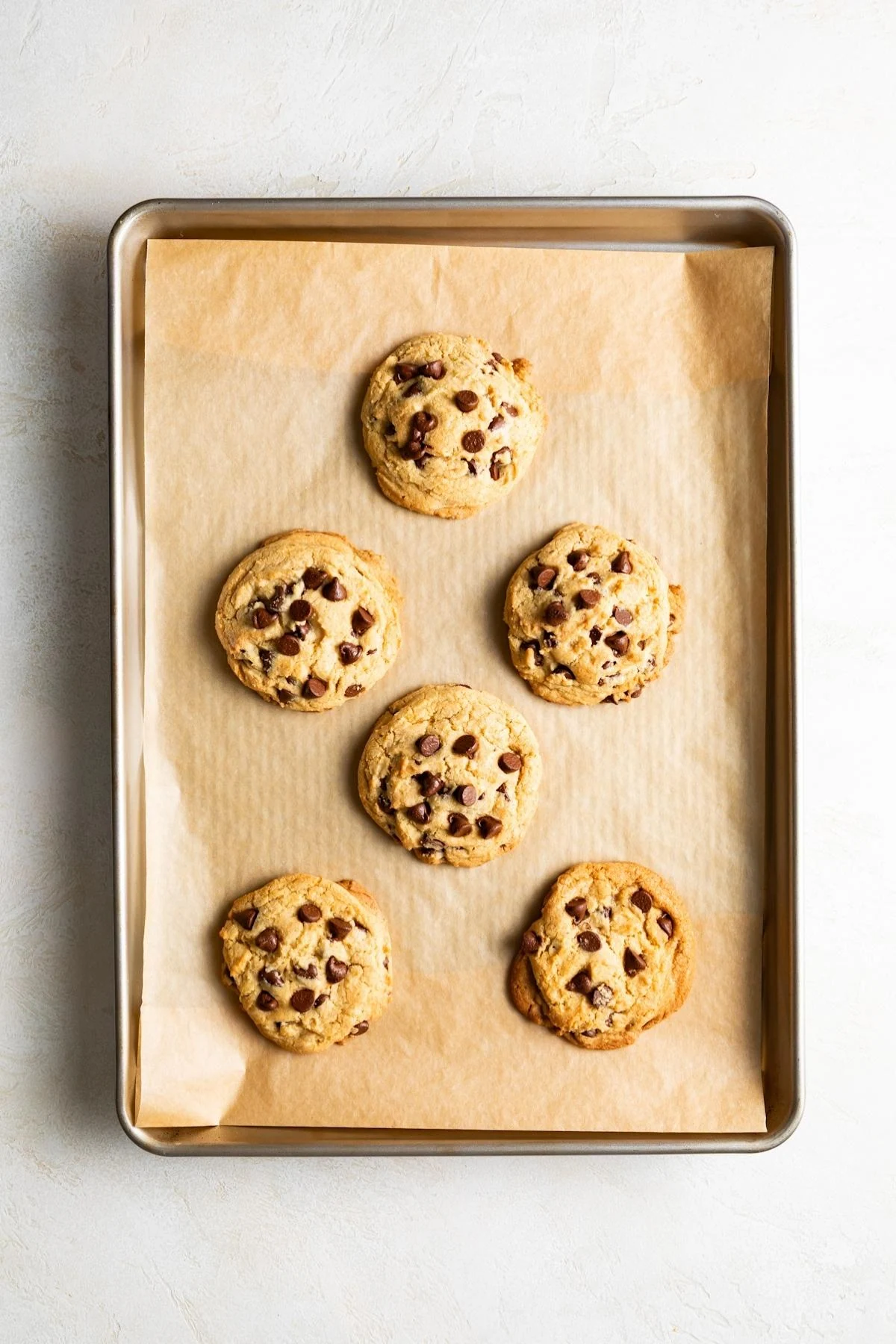 Freshly baked chocolate chip cookies on a baking sheet.