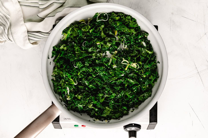 Sauteed garlic, kale, and leeks in a skillet.