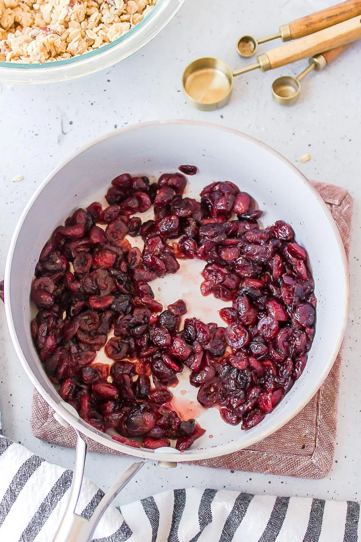 Cooked cranberries in a white skillet for cooking recipes.