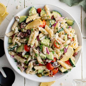 Overhead view of greek pasta salad in a white bowl.