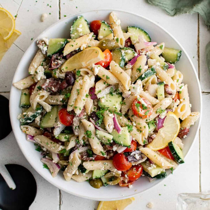 Overhead view of greek pasta salad in a white bowl.