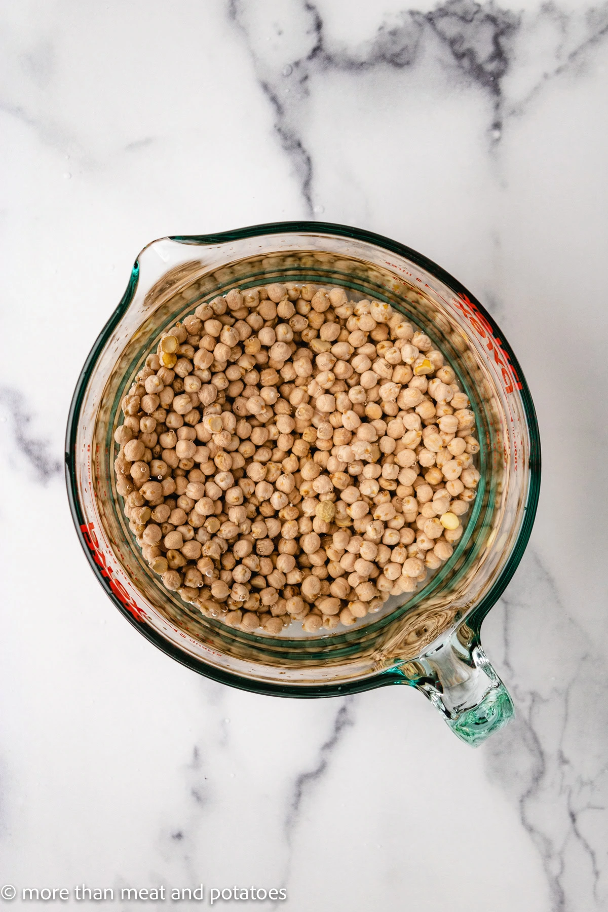 Water poured over chickpeas in a measuring cup.