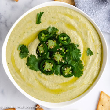 Overhead view of jalape&ntilde;o cilantro hummus in a white dish.
