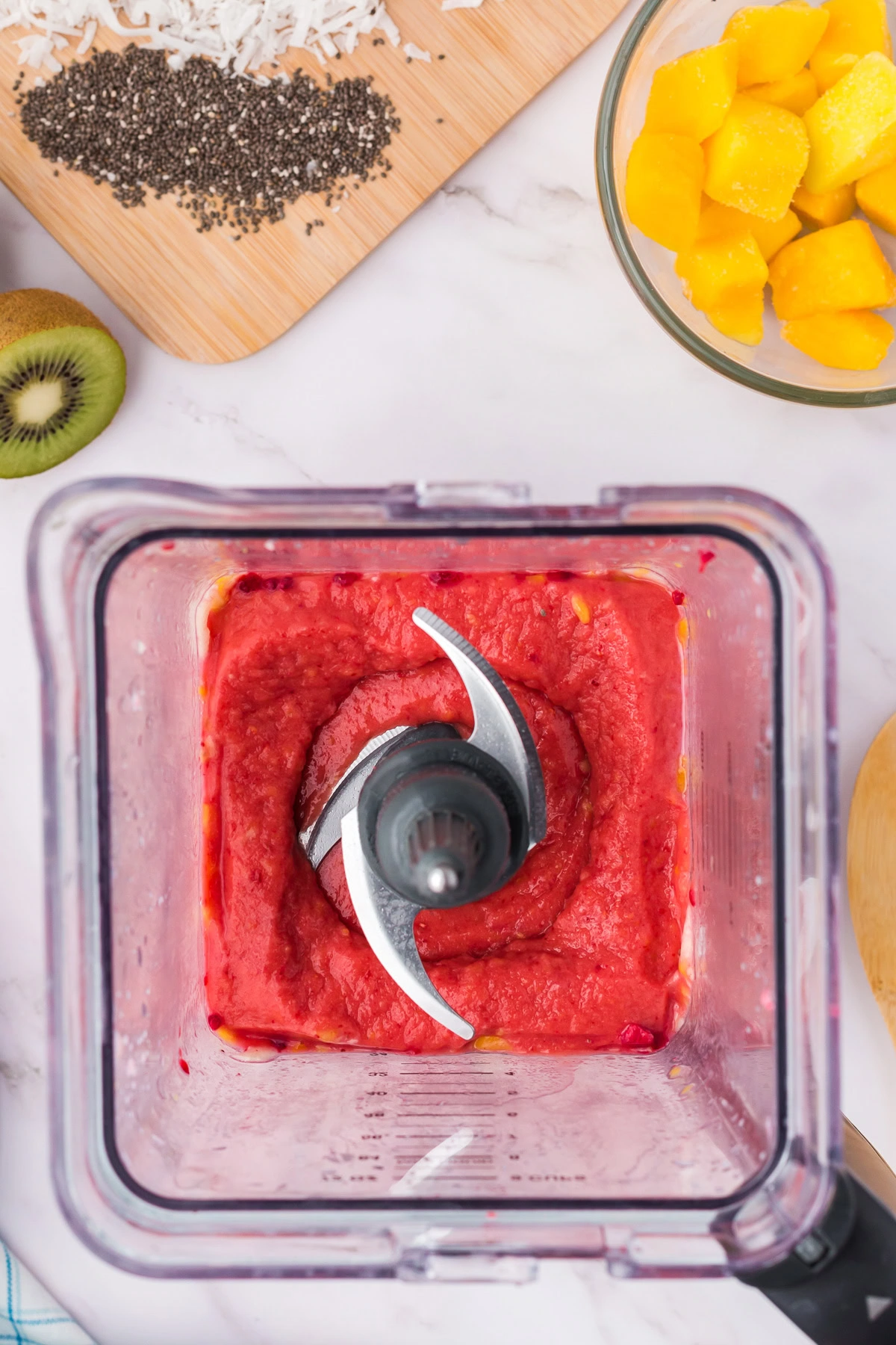 Overhead view of mango raspberry smoothie bowl base in a blender.