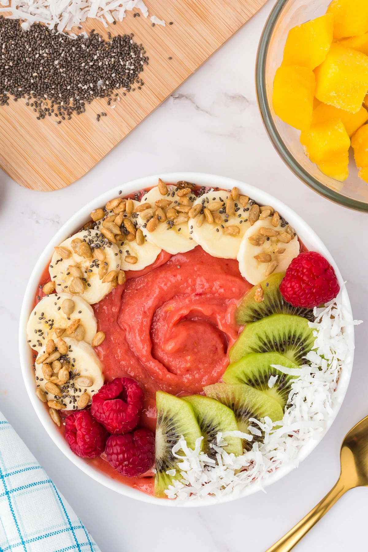 Overhead view of a mango smoothie bowl topped with fruit and nuts.
