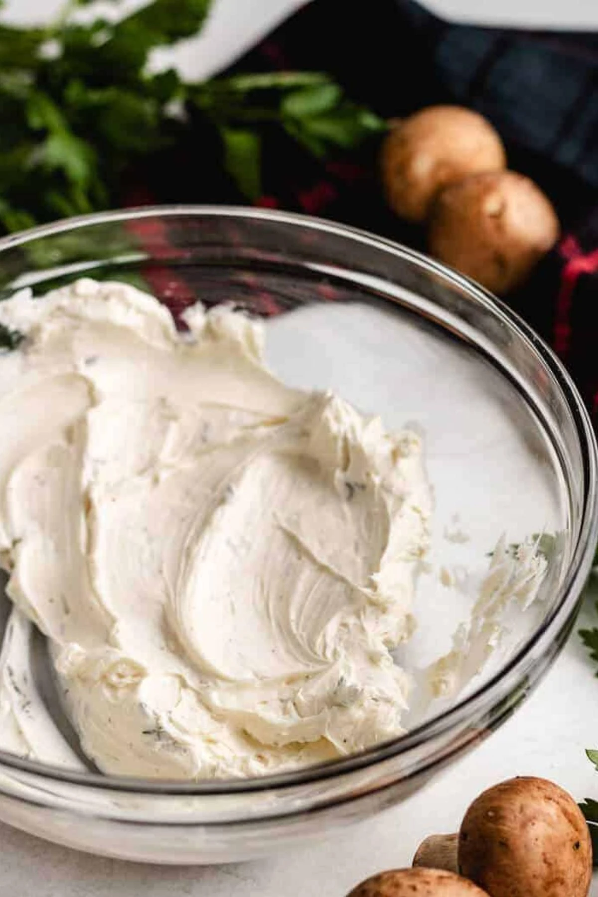 Smooth herb cream cheese in a glass mixing bowl.