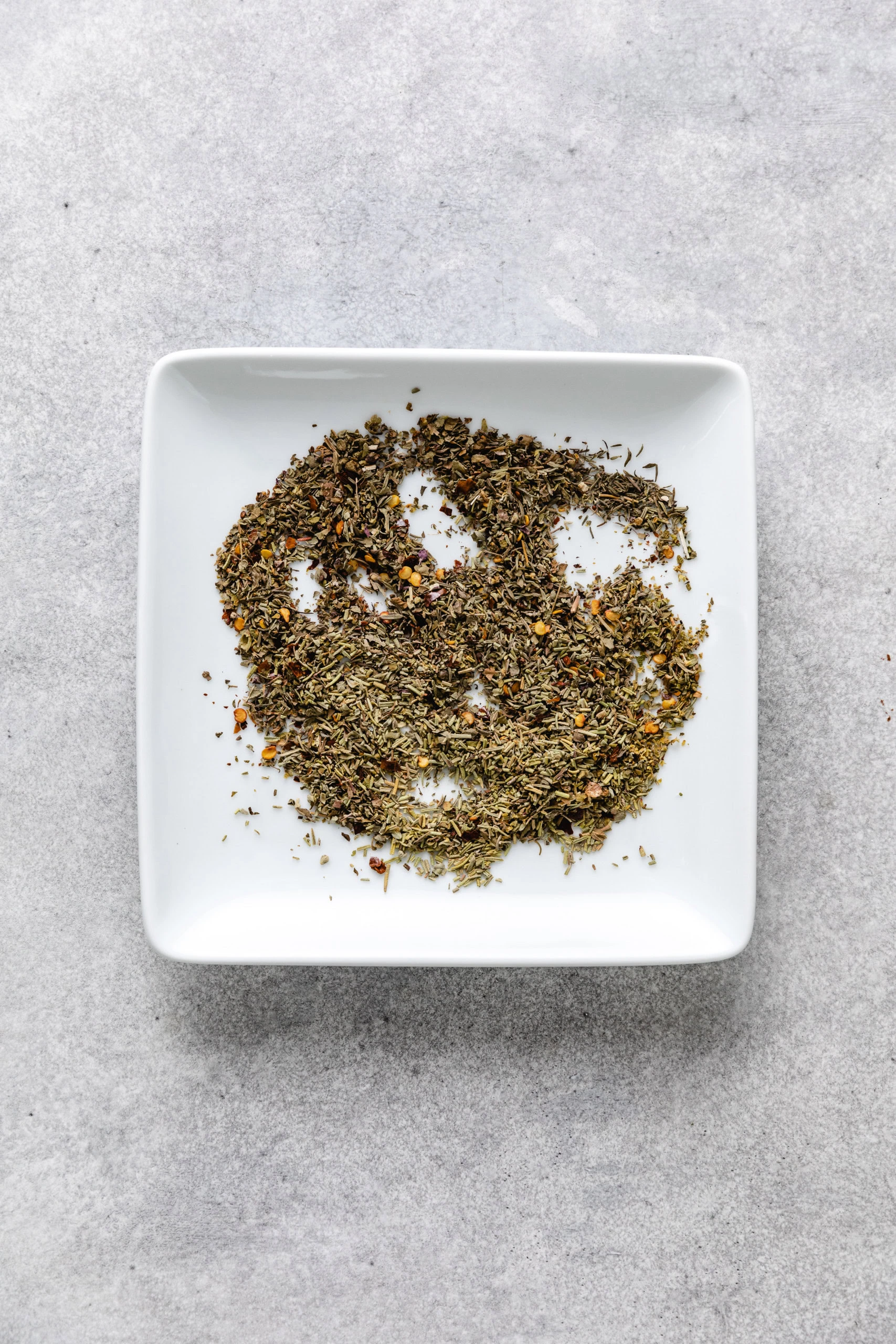 Herb mixture mixed together on a white plate.