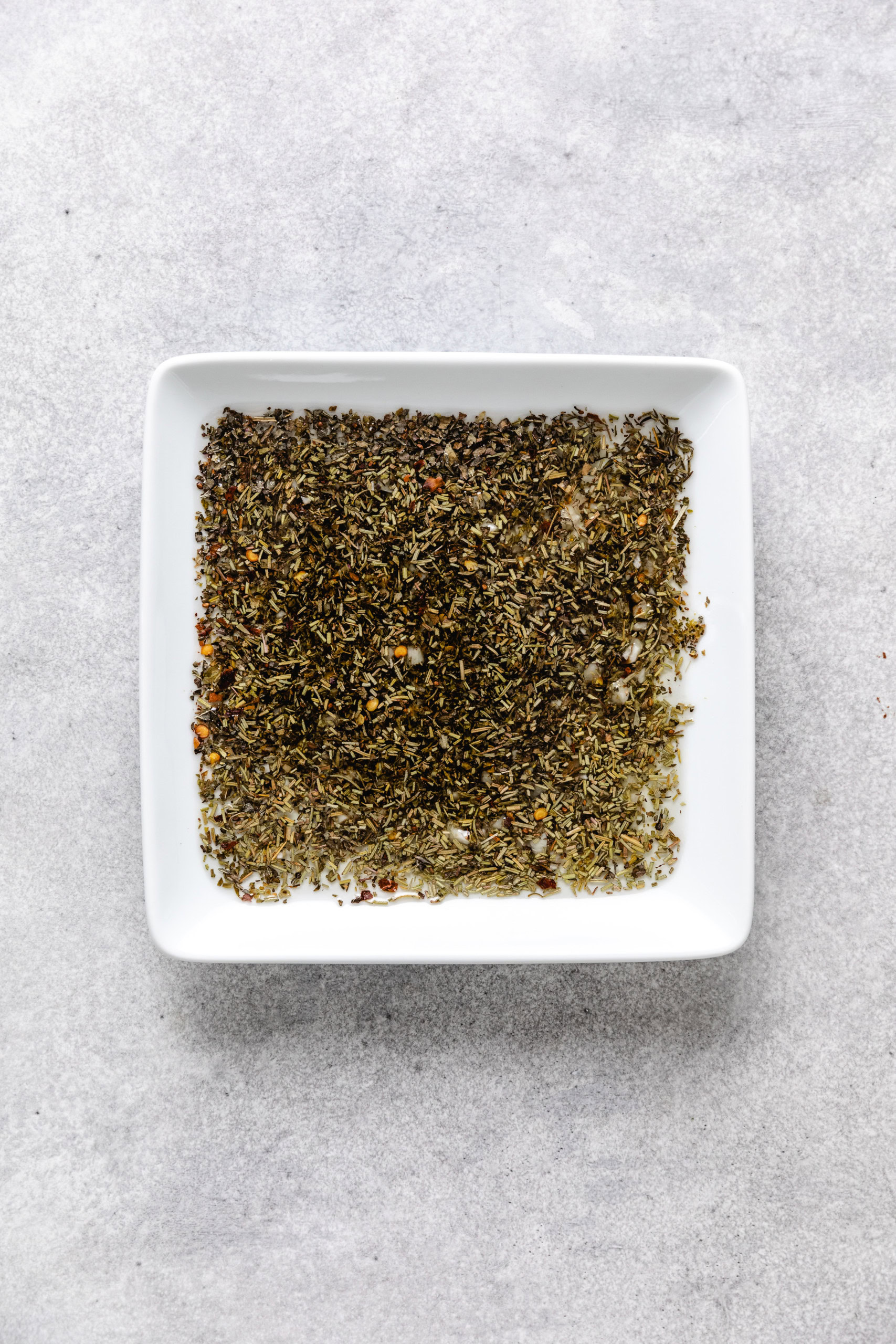 Garlic oil, herbs and balsamic mixed together on a plate.