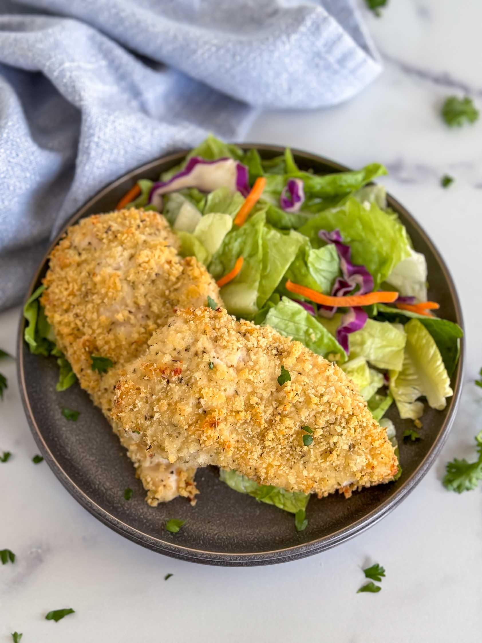 Crispy panko baked chicken on a stack of plates.