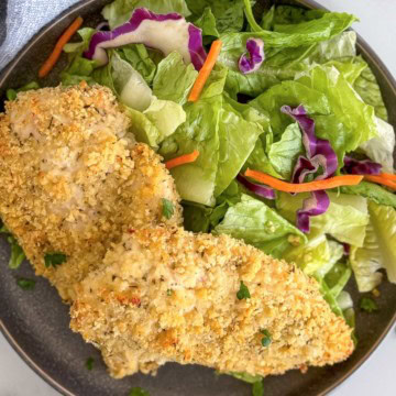 Panko crusted chicken breast next to a light salad.