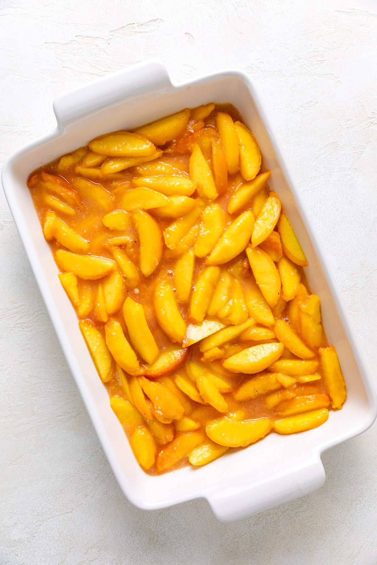 Peach filling spread in a white baking dish.