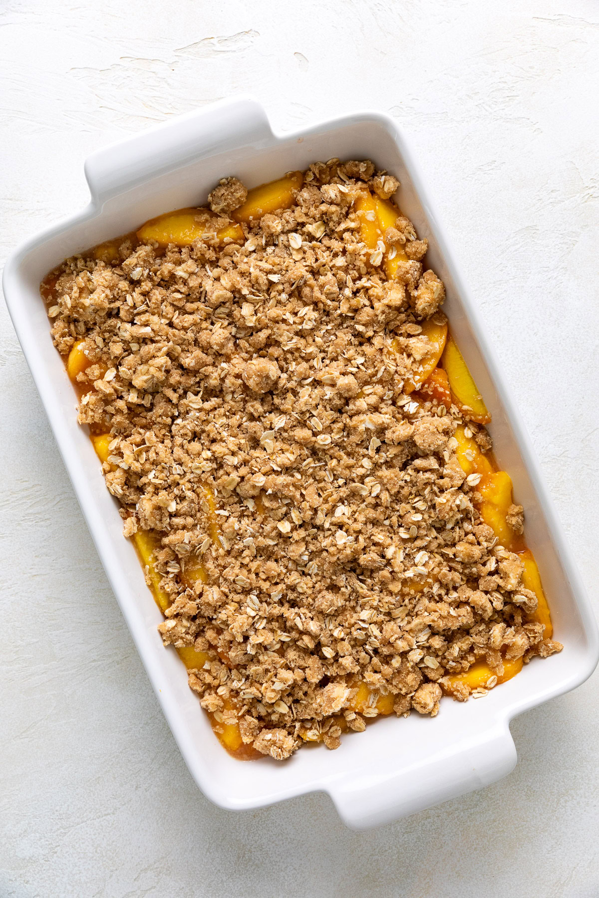 Unbaked peach dessert covered with oat crumble.