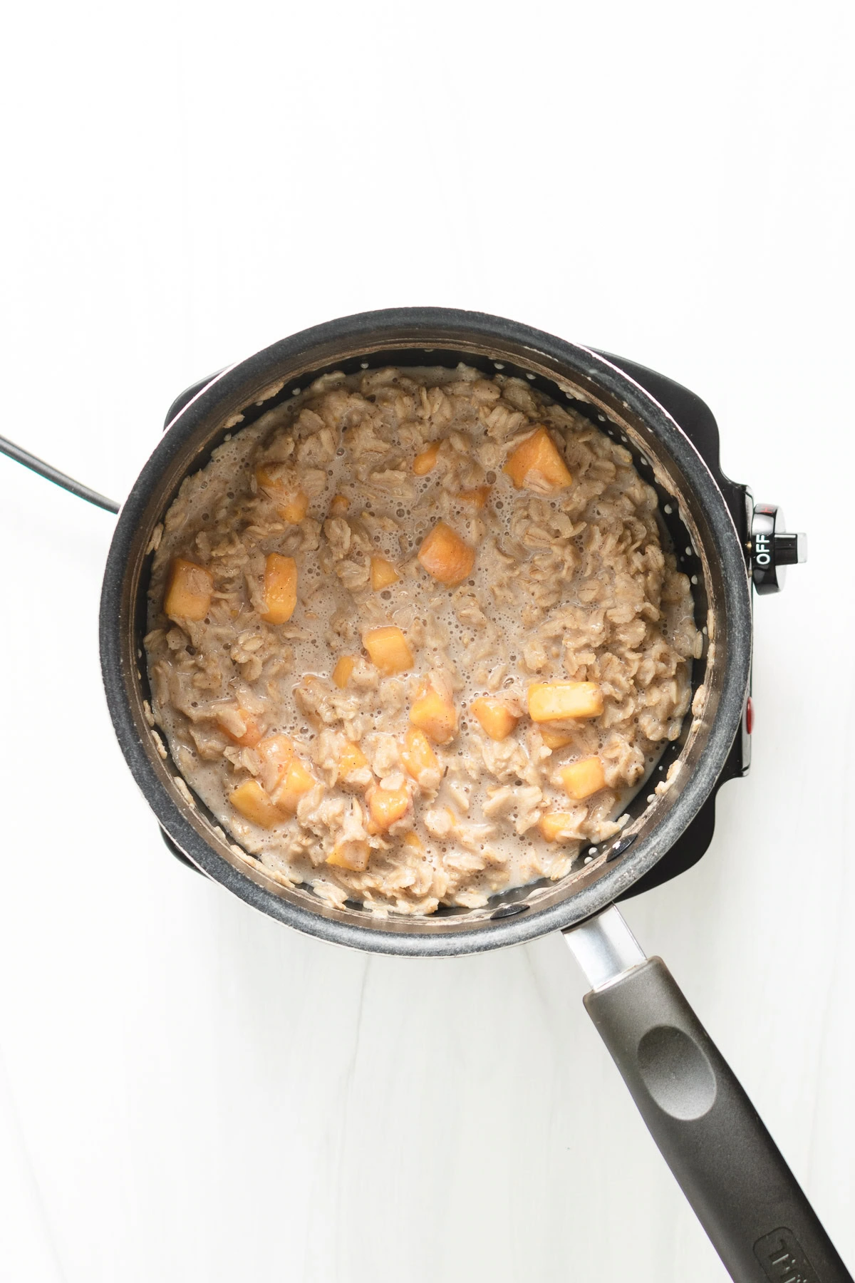 Peaches cooked in with oatmeal in a pan.