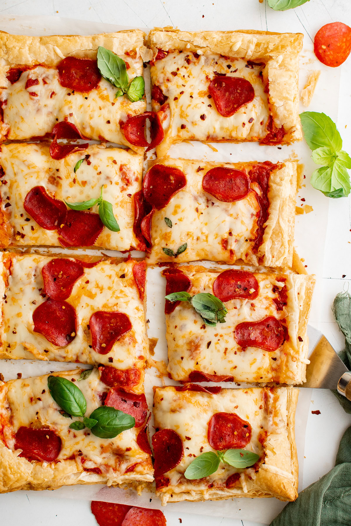 Overhead view of puff pastry pizza garnished with red pepper flakes and fresh basil.