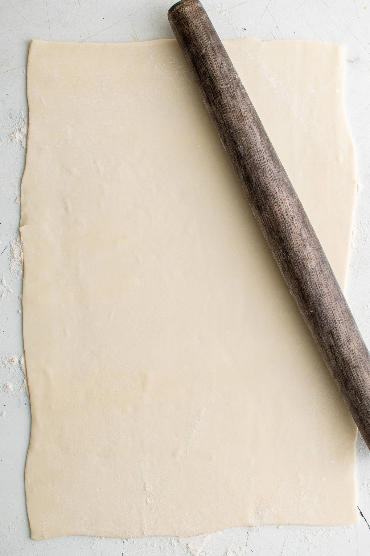 Thawed puff pastry rolled out on a floured surface.