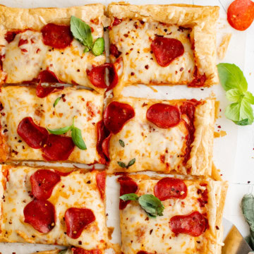 Overhead view of sliced puff pastry pizza topped with pepperoni and cheese.