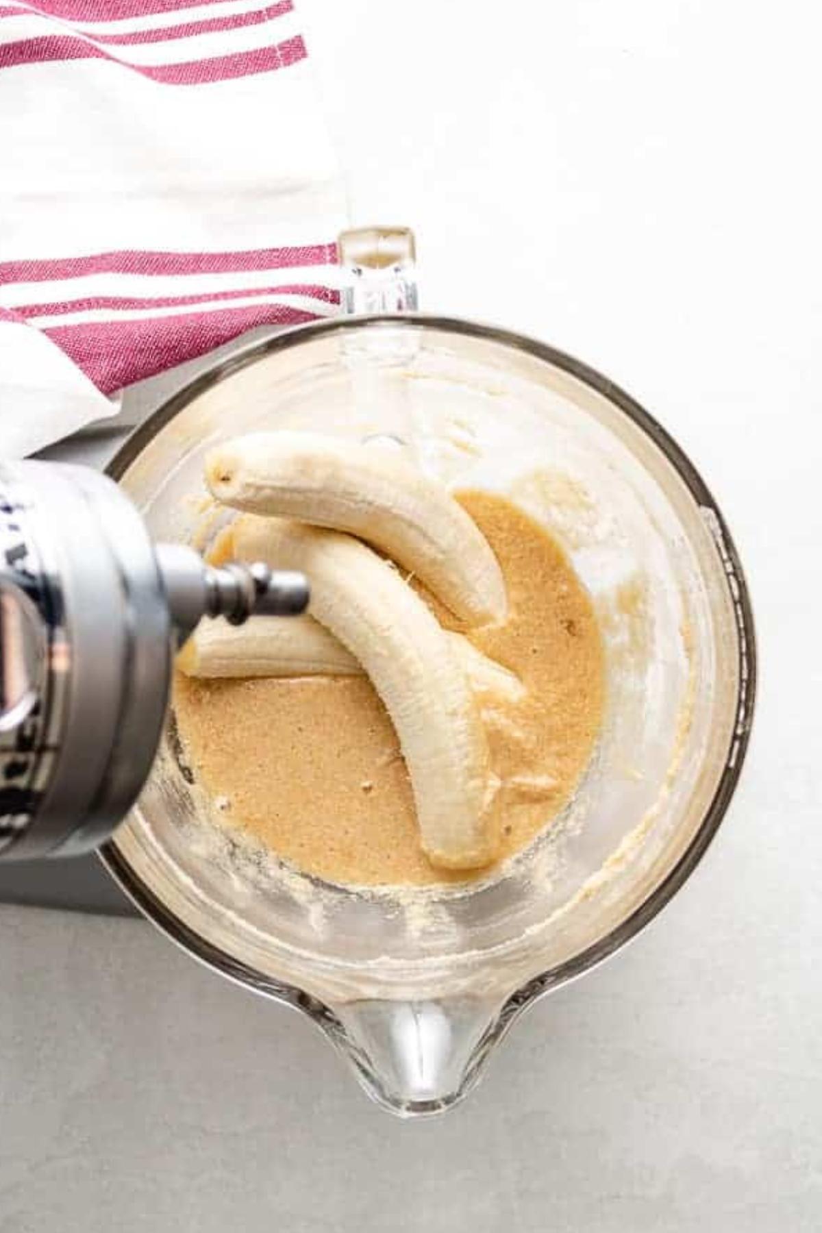 Bananas added to a bowl of sugar, butter, egg mixture.